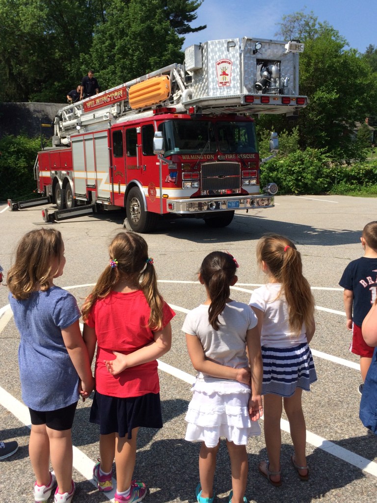Children from the Tiny Tots/Kids Club program listen to the Wilmington Firefighters explain how the ladder truck operates.